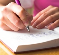 Young female is writing notes and planning her schedule.